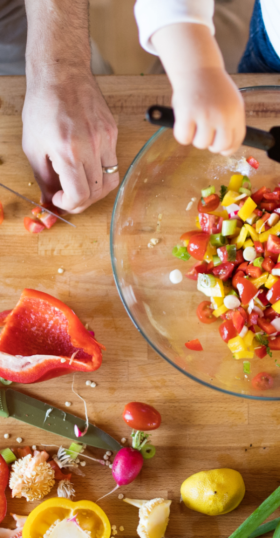 older adult and child mixing peppers in a salad